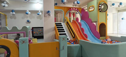 A colorful indoor playground with slides and a ball pit, where a young child plays.