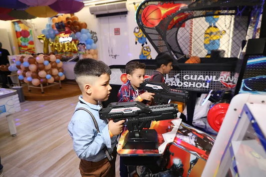 Three boys focused on playing a shooting arcade game in a decorated indoor play zone at Anand Vihar Delhi