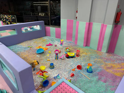 A ball pit filled with children's toys and colorful balls, with a soft purple play structure in the foreground.