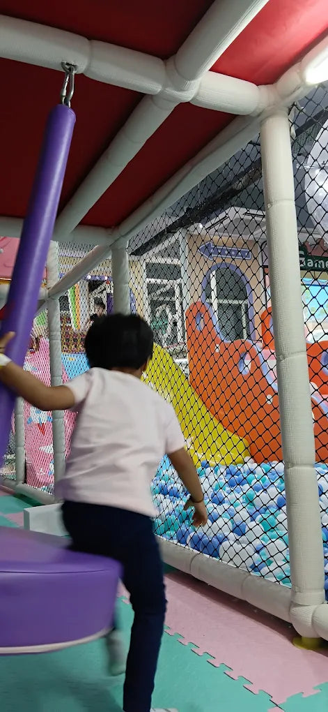 A child plays in a ball pit at an indoor playground.