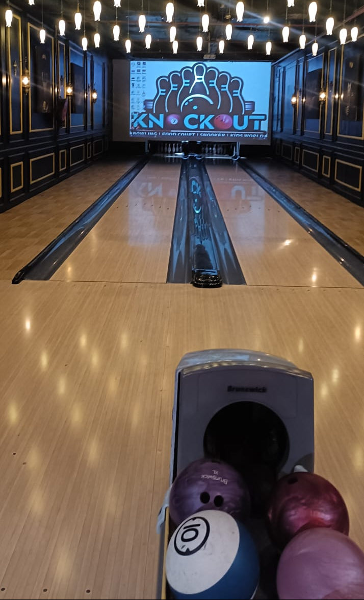 Bowling alley with a "Knockout" screen, bowling balls, and lanes.