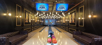 A bowling alley with a screen displaying "Knockout" and bowling balls on the lane.
