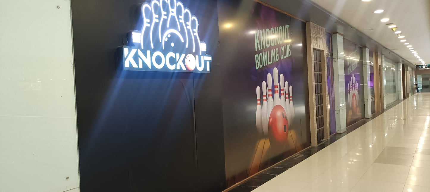 A brightly lit bowling alley with a "Knockout Bowling Club" sign and bowling pins graphic.