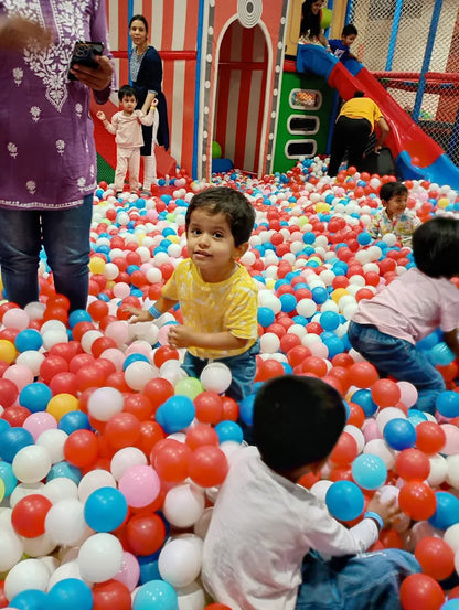 Children play in a ball pit at an indoor playground.