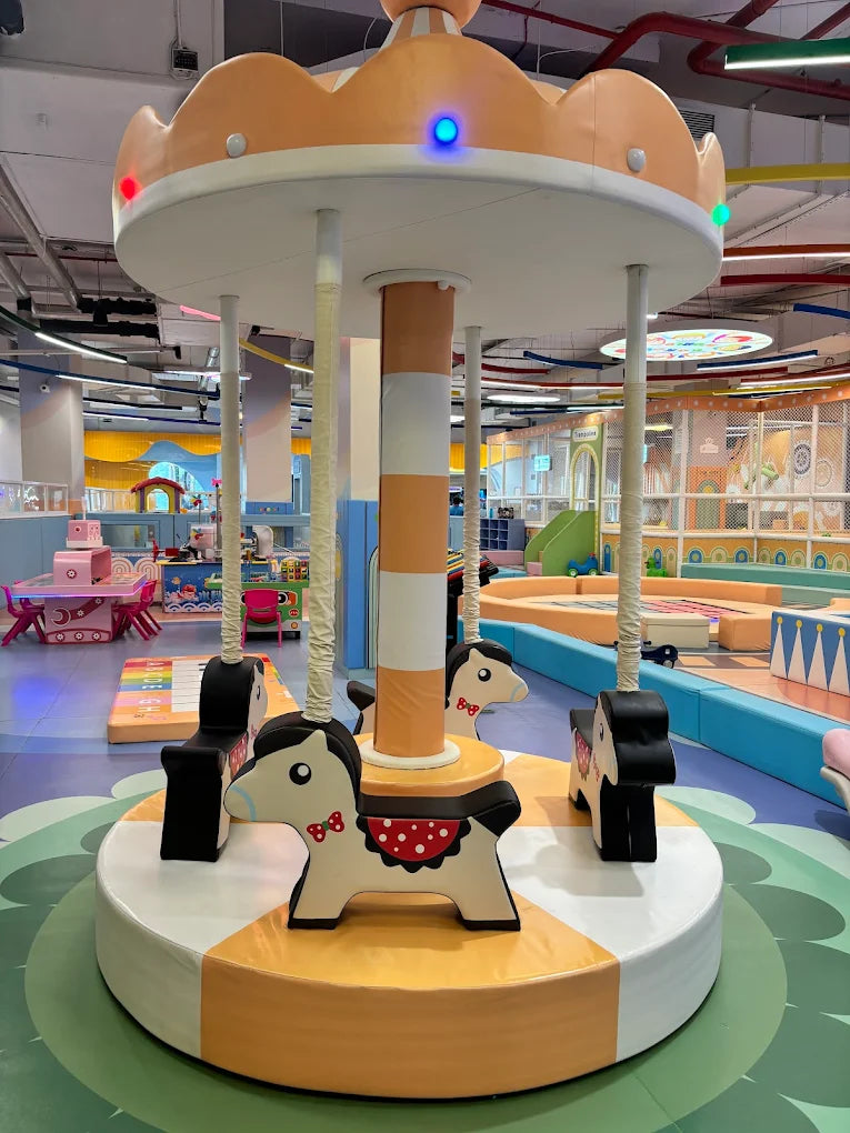 A carousel with horse figures in a brightly colored indoor playground for children.