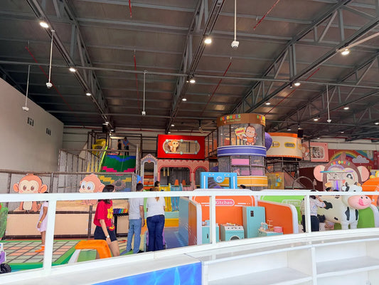 An indoor playground with colorful play structures and children playing.