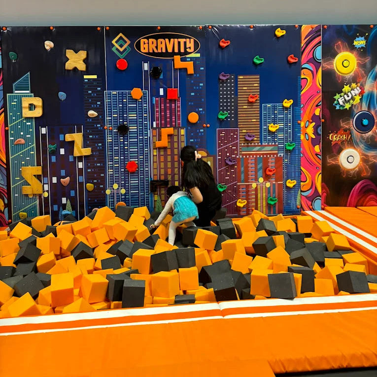 Children playing in a foam pit with a colorful urban backdrop.