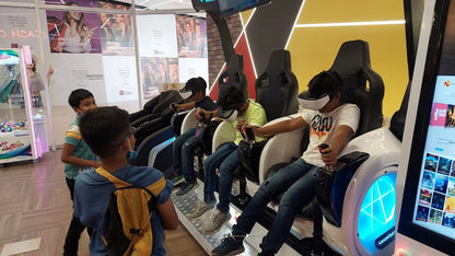 Children wearing VR headsets play a virtual reality game in a brightly lit arcade.