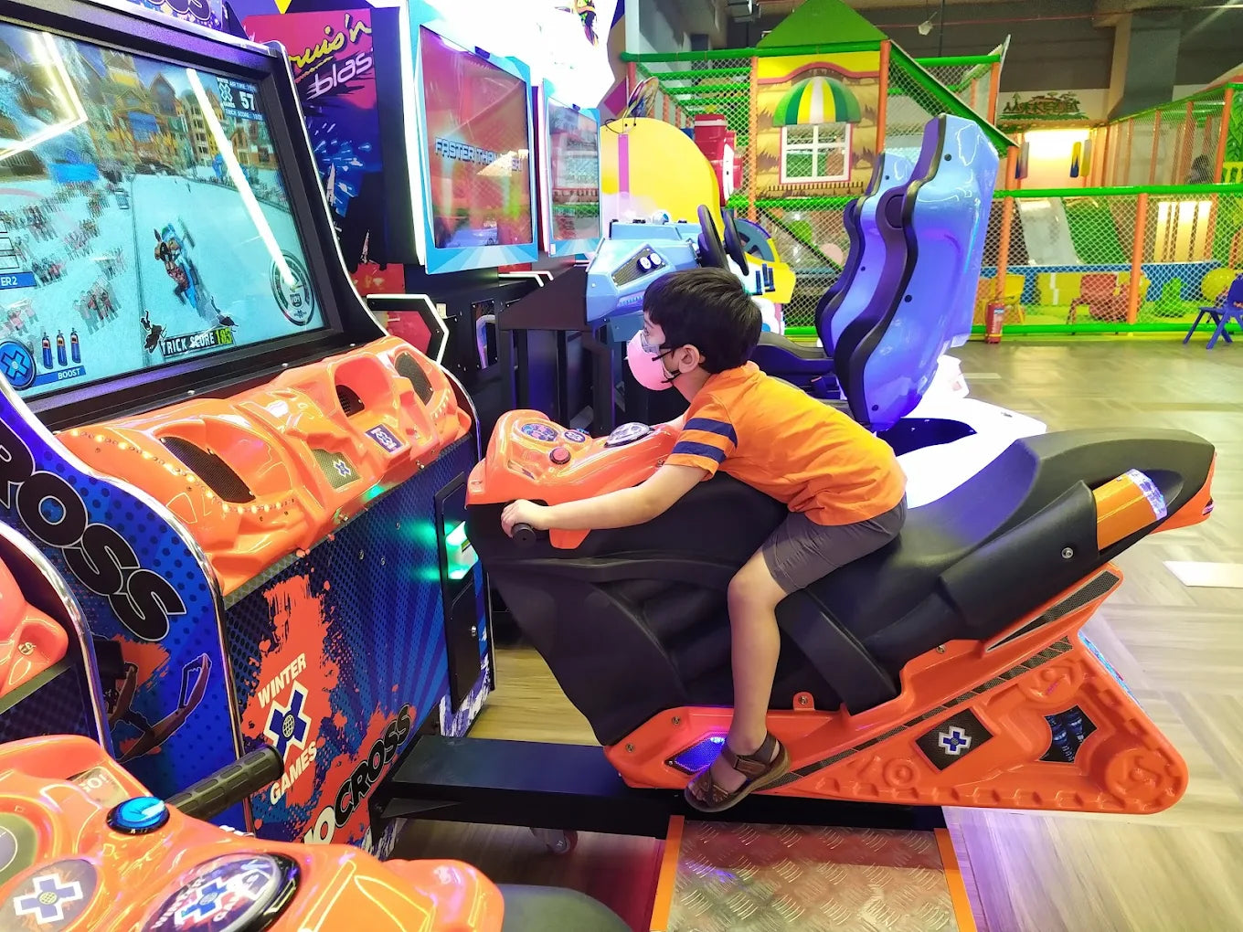 A child plays a motorcycle racing arcade game in an indoor amusement park.