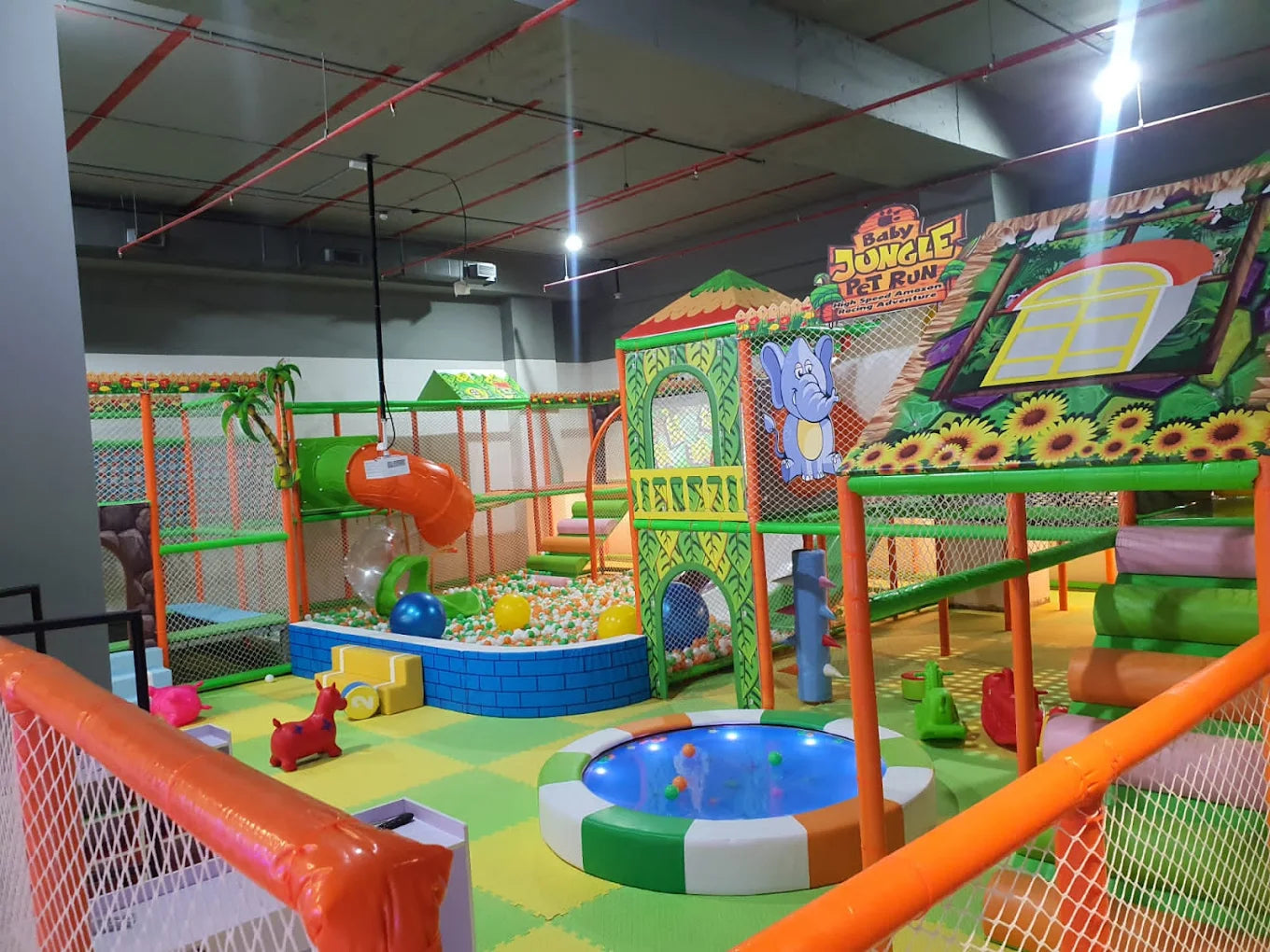 A colorful indoor playground for young children with slides, ball pits, and climbing structures.
