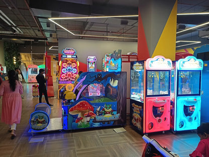An arcade with various game machines and a few people playing.