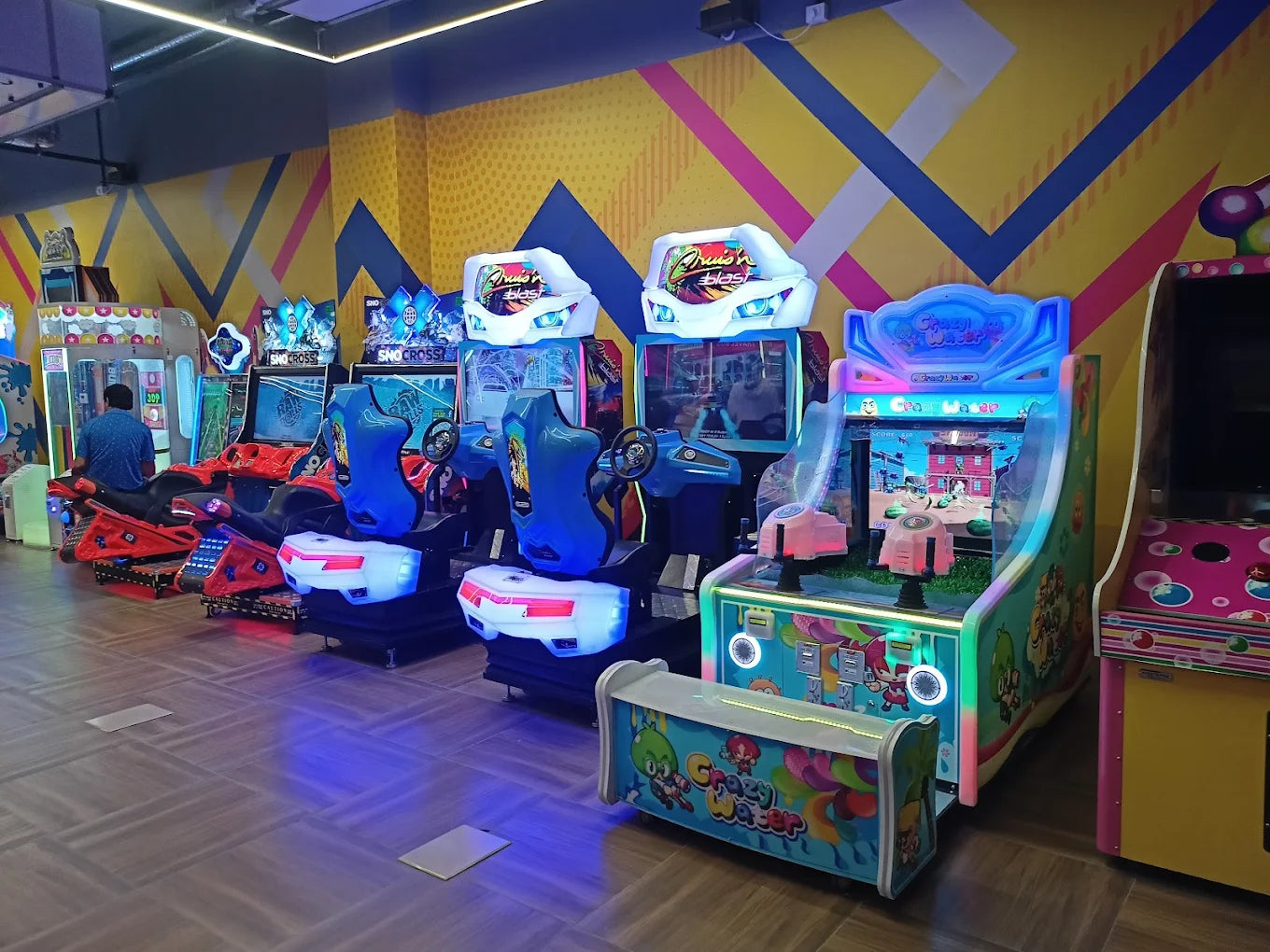 Arcade with racing and shooting games. A person plays a motorcycle racing game.
