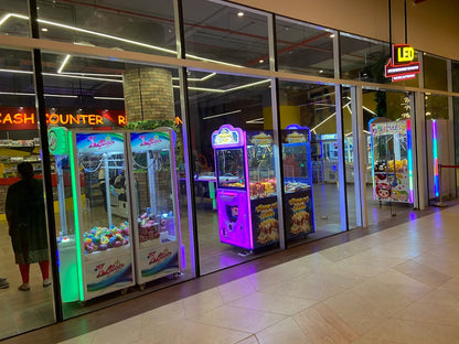 Arcade claw machines and games are displayed in a brightly lit indoor entertainment center.