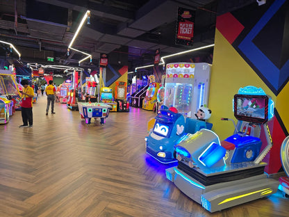 An arcade with various game machines and a few adults playing.