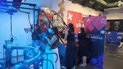 Young adults play a VR shooting game in an arcade.