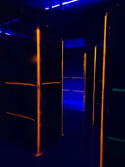Dark indoor laser tag arena with glowing orange and blue lights.