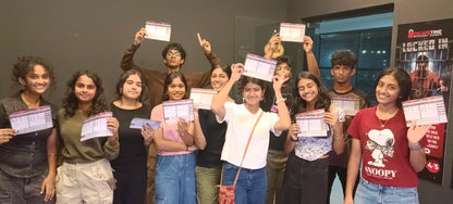 A group of young adults poses for a photo, holding up papers after completing an escape room challenge.