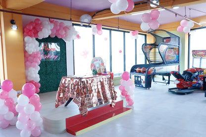 Decorated room with balloons, a table, and arcade machine.