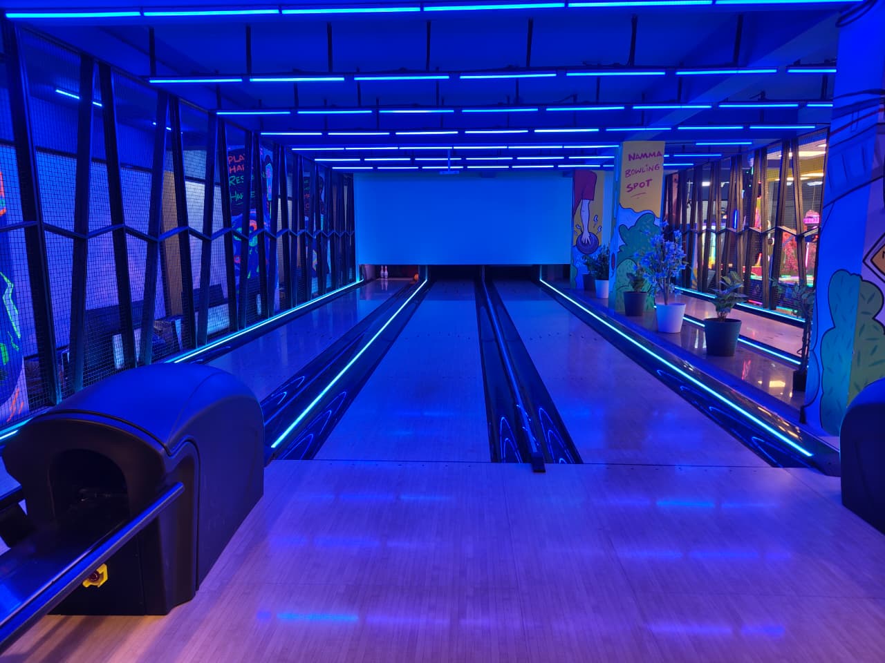 A bowling alley with blue neon lights and wooden lanes.