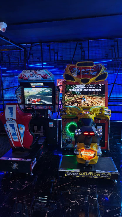 Arcade racing games with a motorcycle theme, set in a dimly lit arcade with blue neon lights.