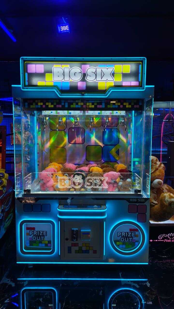 A brightly lit "Big Six" claw machine filled with plush toys, likely in an arcade.