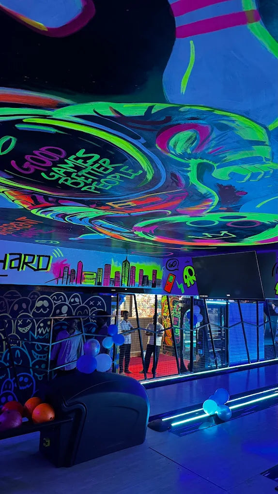 A neon-lit bowling alley with graffiti art and people.