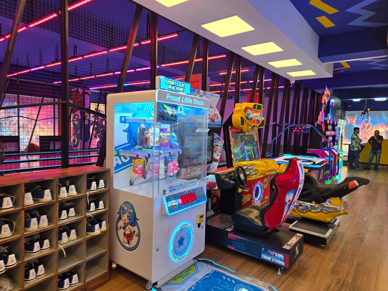 Arcade with colorful games and a shoe rack, two young men stand in the background.