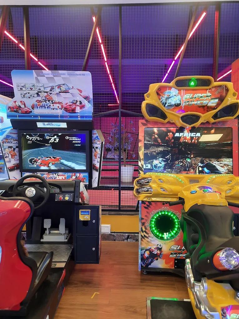 Arcade racing game machines with bright lights and colorful graphics.