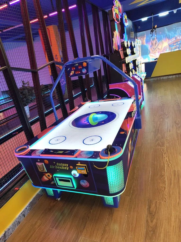 An air hockey table in an arcade, with colorful lights and other games in the background.