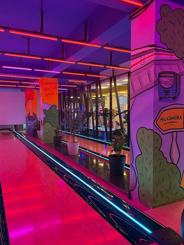 A brightly lit bowling alley with neon lights and cartoon murals.