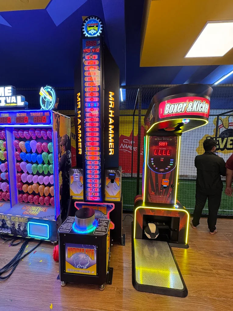 Arcade games, including a hammer strength tester and a boxing game, are displayed in a brightly lit entertainment center.