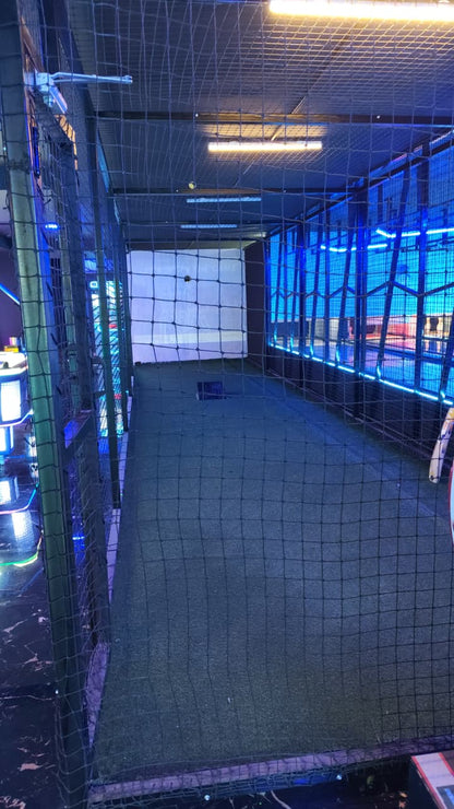 An indoor batting cage with blue lights and a turf floor.