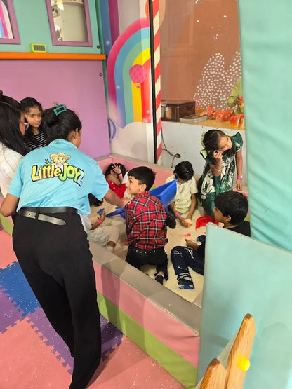 Children play in a ball pit while an adult supervises.