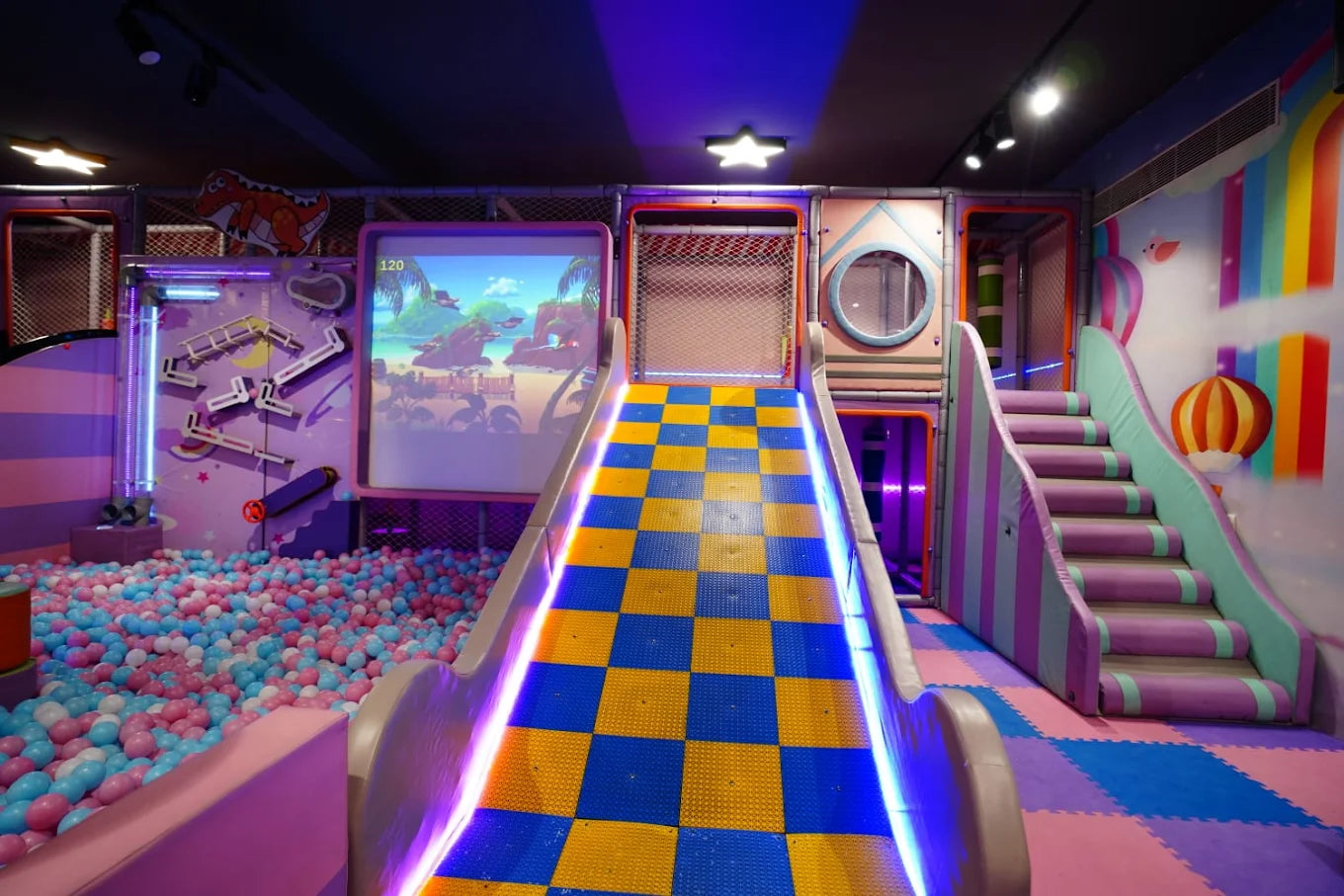 A colorful indoor playground with a ball pit, slide, and stairs, designed for children.