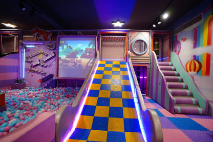 A colorful indoor playground with a ball pit, slide, and stairs, designed for children.