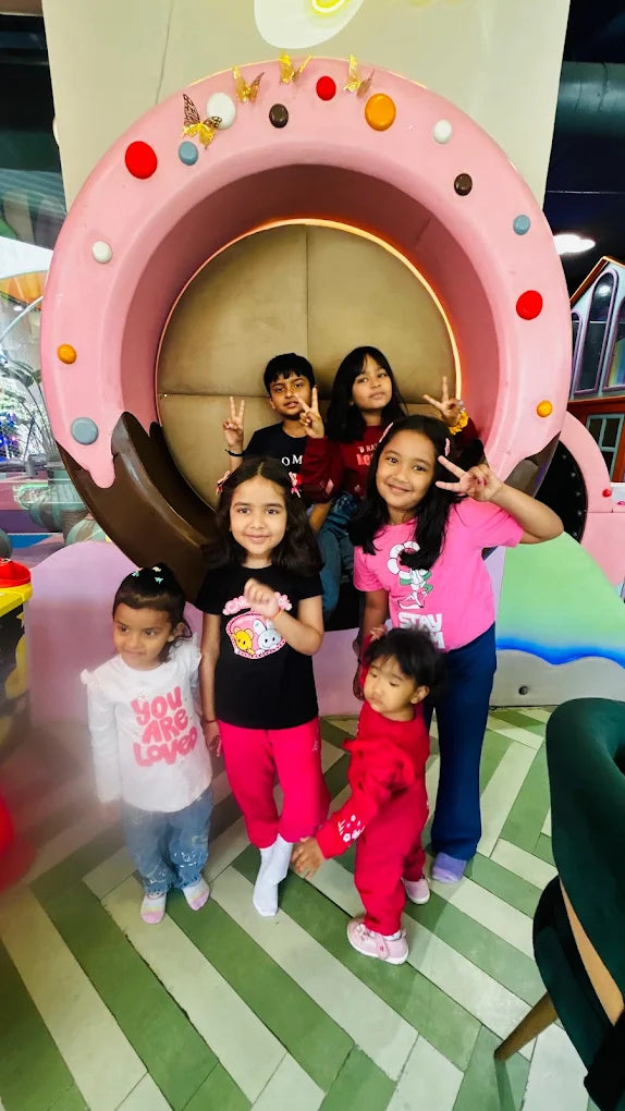 A group of young children pose for a photo in a colorful, playful indoor setting.