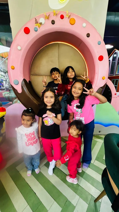 A group of young children pose for a photo in a colorful, playful indoor setting.