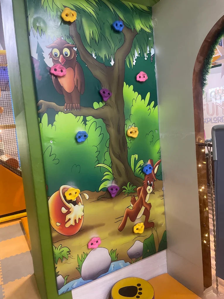 A colorful climbing wall with cartoon animals for children to play on.