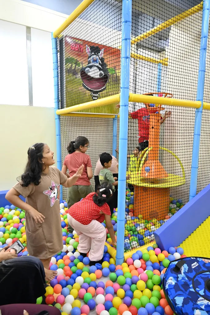 Children play in a ball pit at an indoor playground.