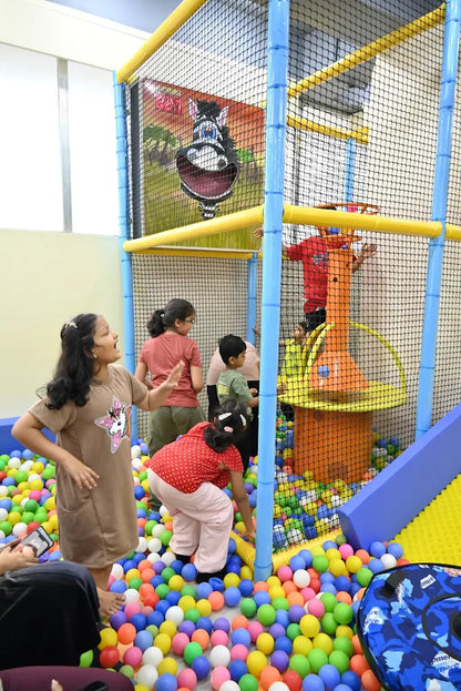 Children play in a ball pit at an indoor playground.