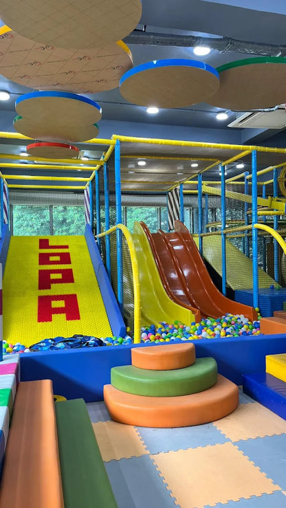 A colorful indoor playground with slides, a ball pit, and soft seating for children.