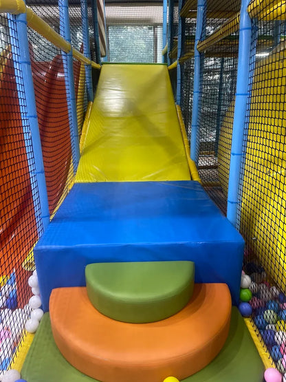 A colorful indoor playground slide with soft steps for young children.