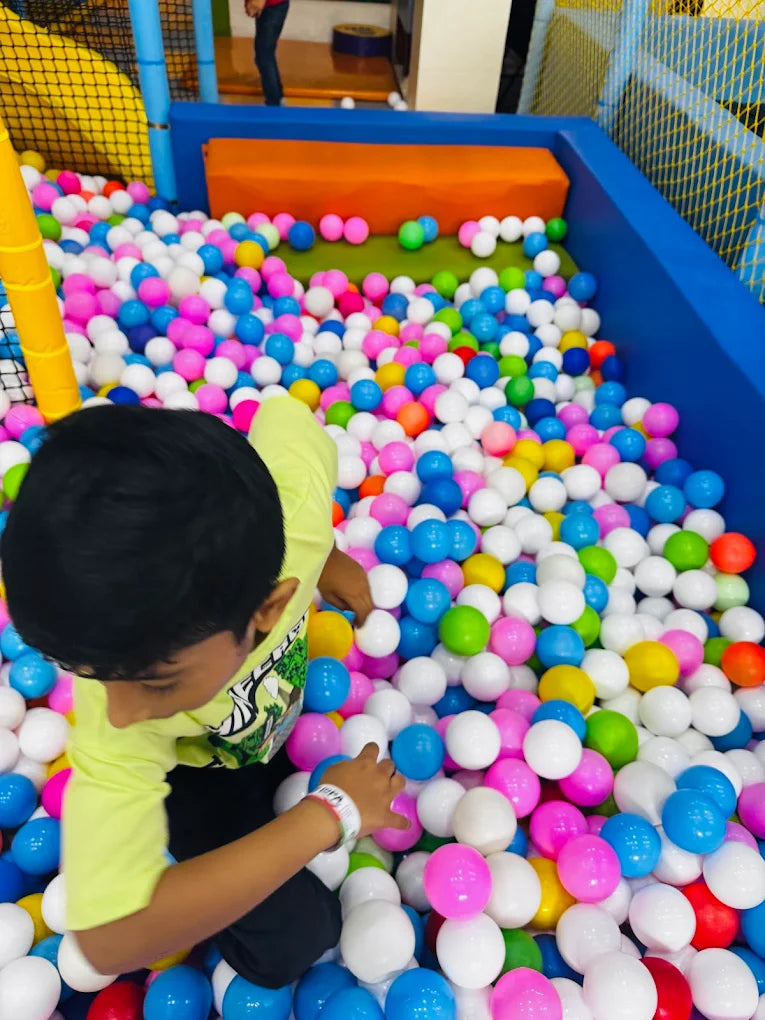 A young boy plays in a ball pit filled with colorful balls.