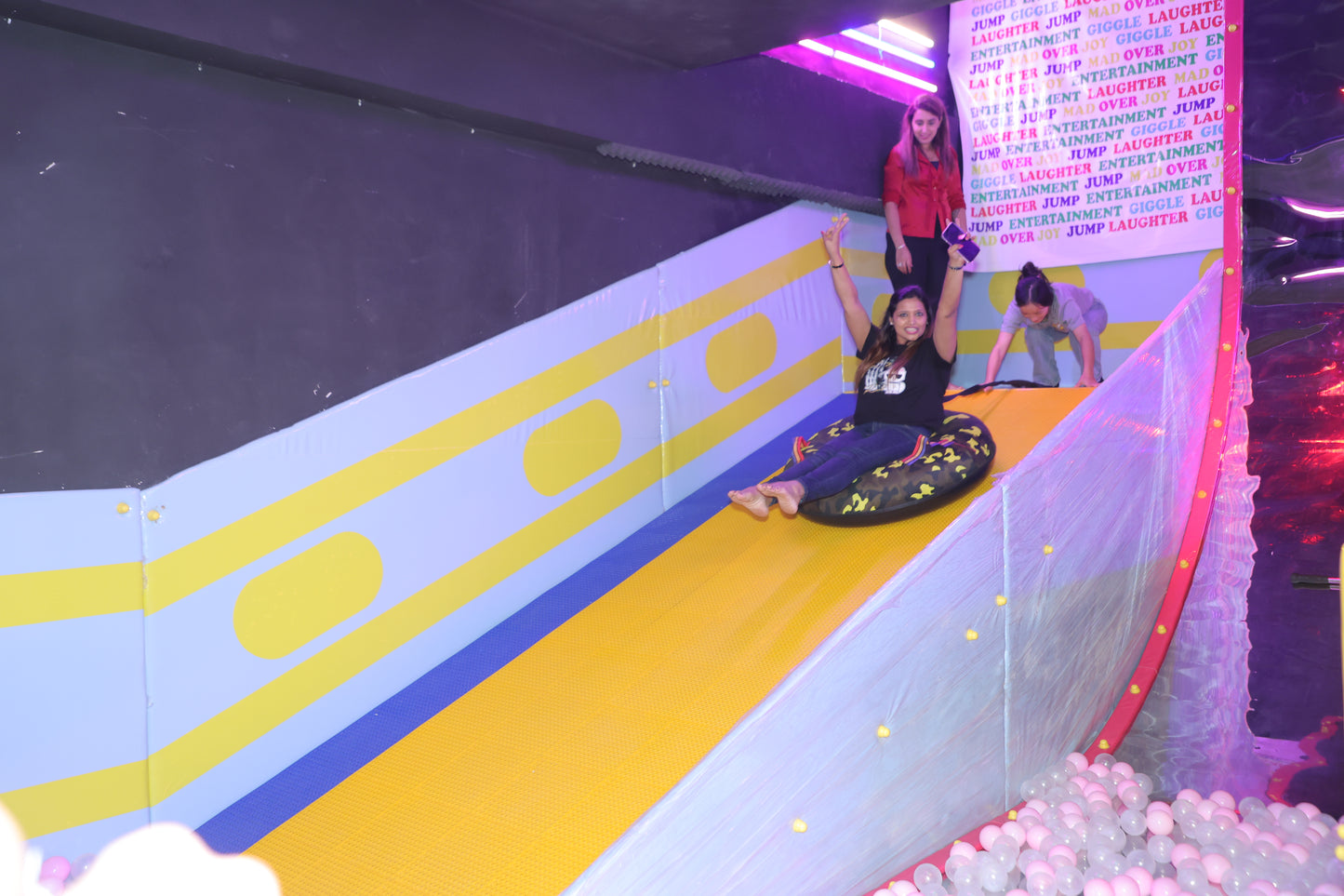 Children and Adults playing on a colorful slide with a ball pit at the bottom