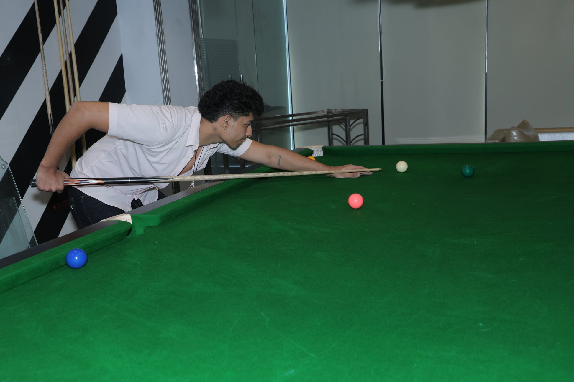 Person playing pool in a room with striped walls