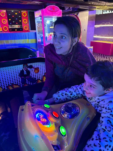 A woman and a child play an arcade game in a brightly lit entertainment center.