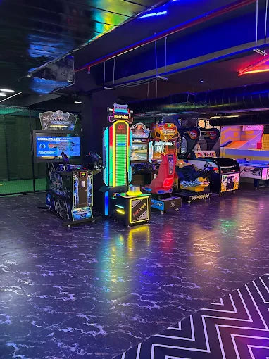 Arcade with colorful, glowing games and a dark, marbled floor.