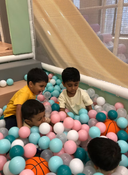 Young children play in a ball pit filled with colorful balls.