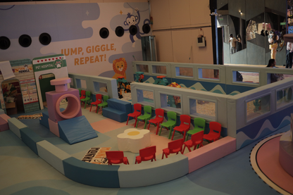 A colorful indoor playground with soft play structures and seating for children.