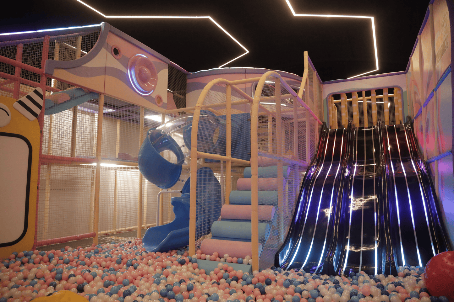 A colorful indoor playground with slides and a ball pit for children.